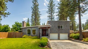 A two-story house with a brick exterior, a front yard, and a garage. - Parkway House - PICKLEBALL COURT- Dog Friendly  - Basketball - FAMILY PERFECT  (Nine Mile Falls)