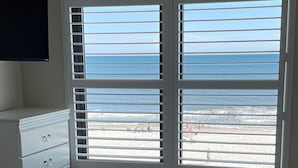 Une chambre à coucher avec un lit, une commode et une fenêtre donnant sur la plage.