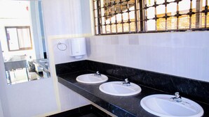 A bathroom with two sinks, a hand dryer, and a window with metal bars.