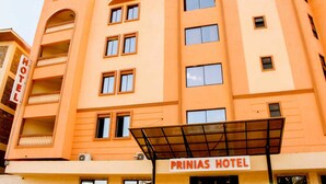 Un hotel de varios pisos con fachada plana, balcones y un área de entrada cubierta.