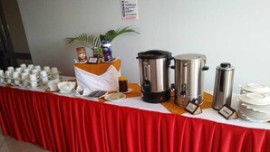 Un montaje tipo bufé con mantel rojo, cafeteras y diversos recipientes de comida.