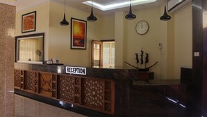 Una zona de recepción con mostrador de mármol, un reloj y un cuadro en la pared.