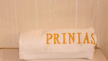 Une serviette blanche avec le texte « PRINIAS » brodé, posée sur une surface en bois.