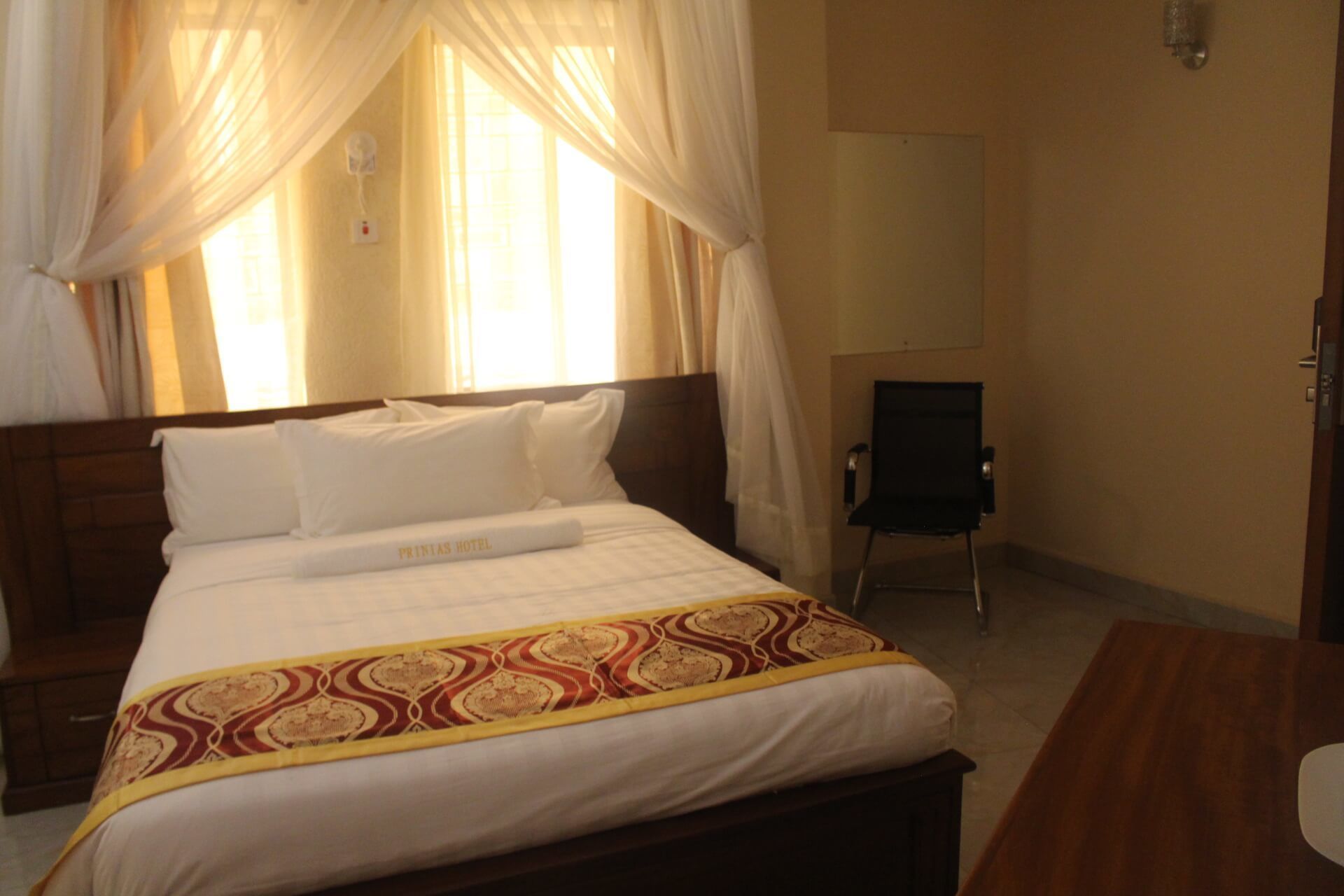 Ein Hotelzimmer mit Bett, Nachttisch, Sessel und Fernseher.