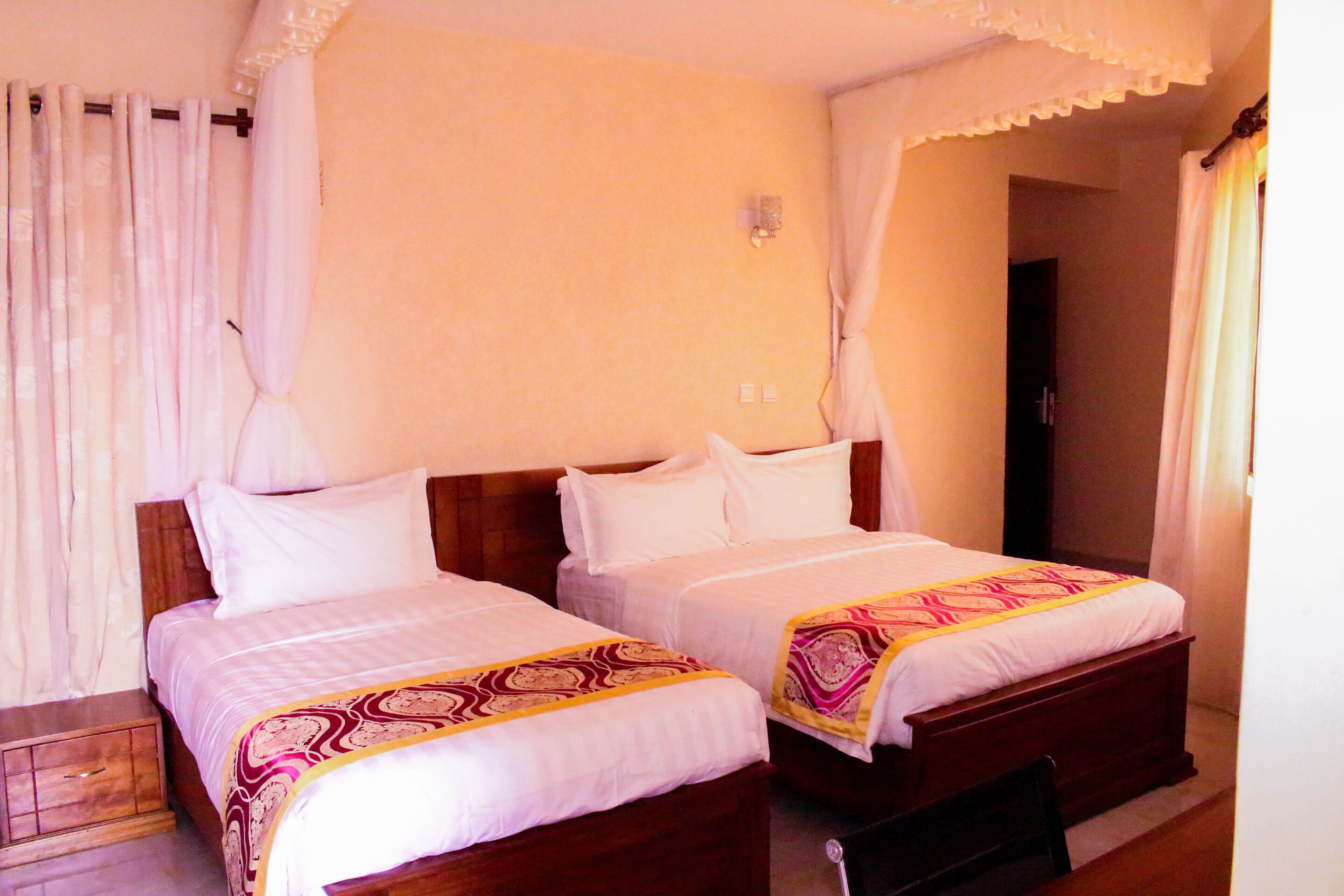 Quarto com duas camas, cada uma com roupa de cama branca e um cobertor estampado.