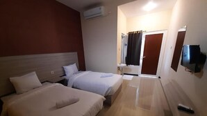Ett hotellrum med två sängar, en TV, ett handfat och en spegel.