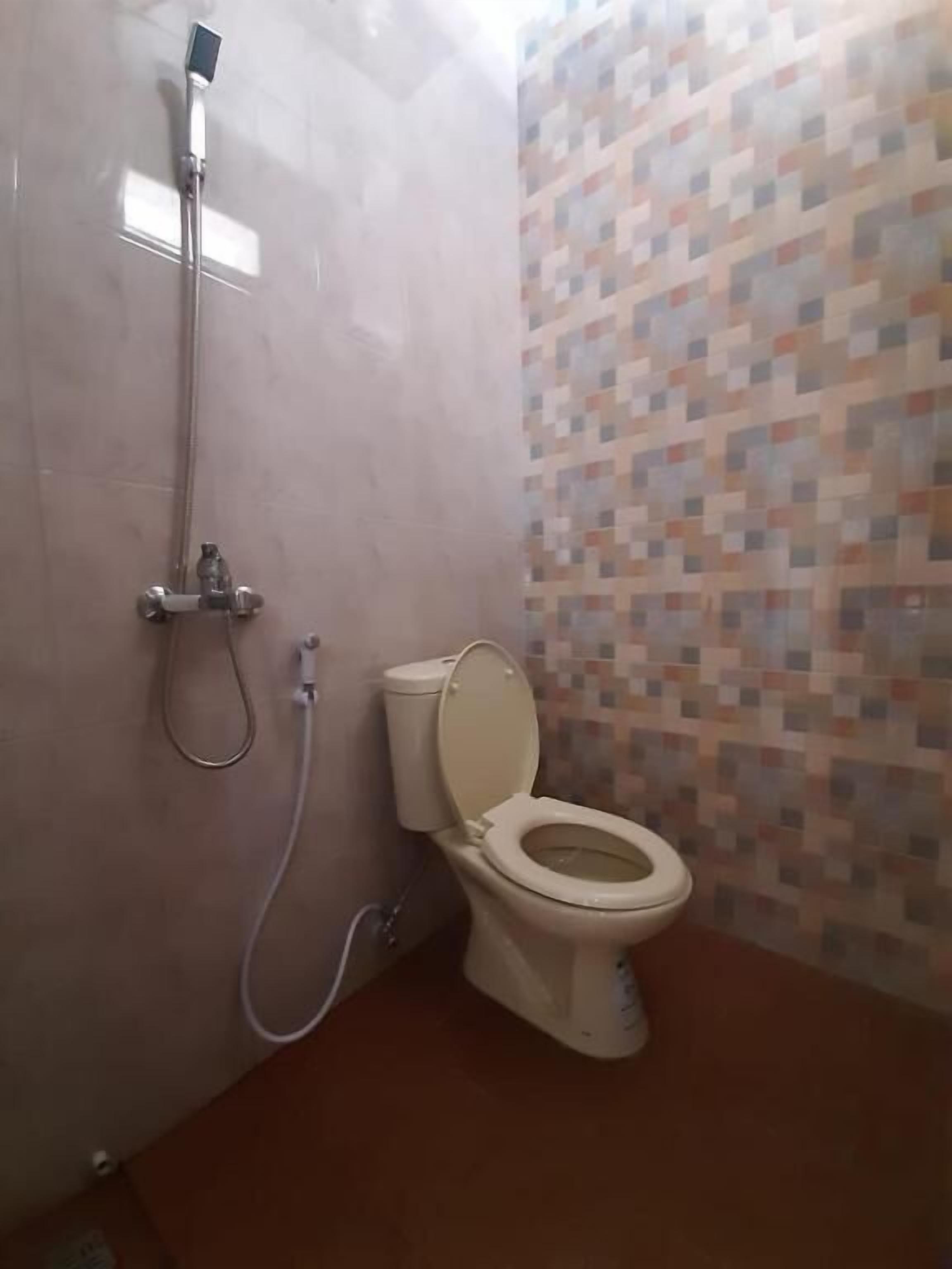 Ein Badezimmer mit Toilette, Dusche und Fliesen.