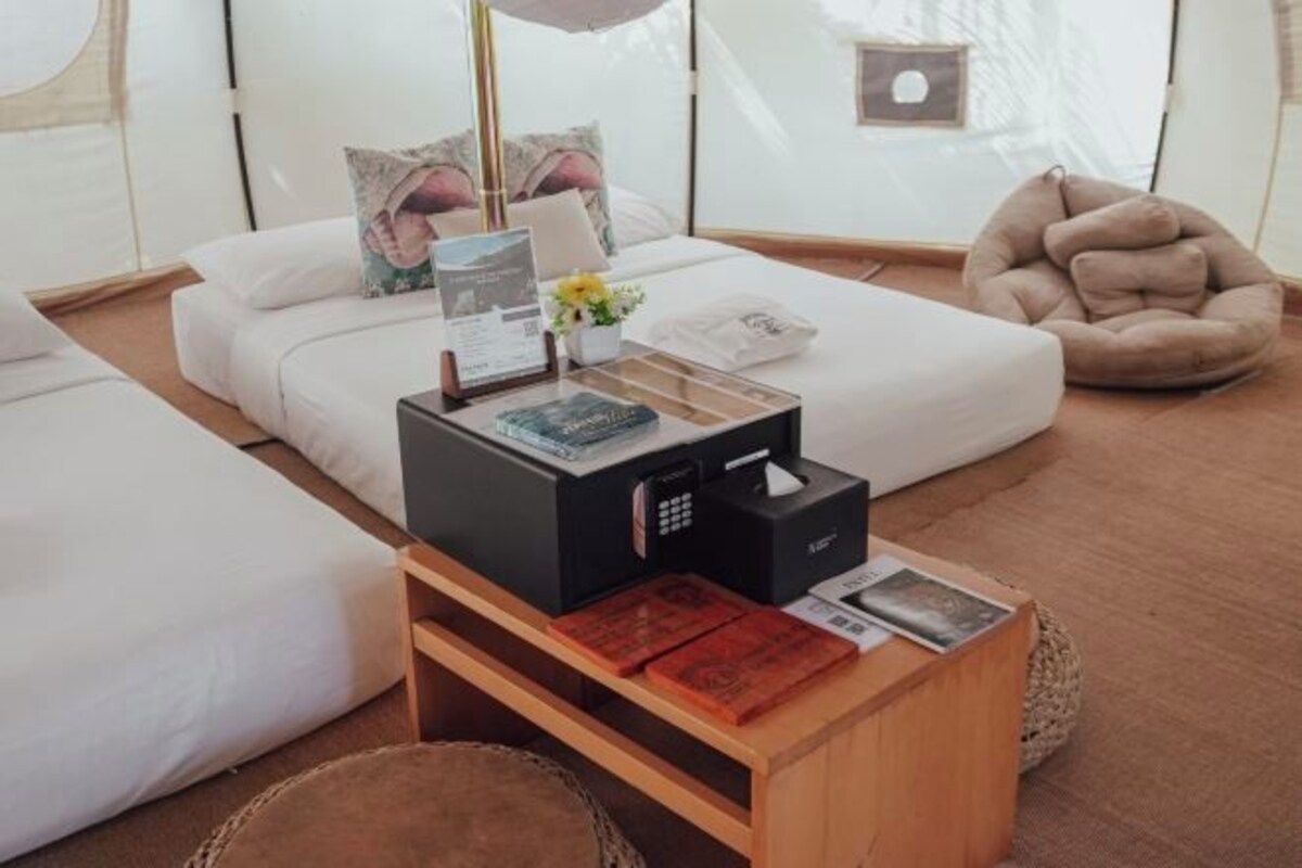 A modern hotel room with a white sofa, a wooden coffee table with a book and a tissue box, and a beige bean bag chair.