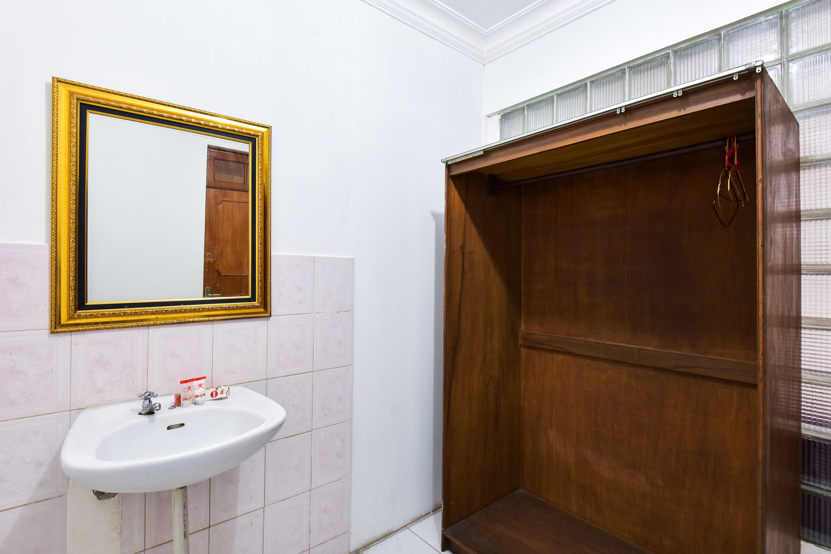 A bathroom with a white sink, a mirror with a gold frame, and a wooden shower enclosure.