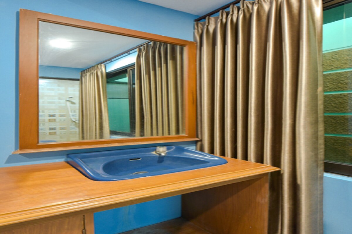 A bathroom with a wooden vanity, a blue sink, and a mirror.