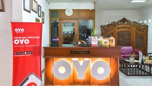 A reception desk with a sign reading "Receptionist" and a large illuminated sign with "OYO" letters. - Hotel Sekar Ayu (Yogyakarta)