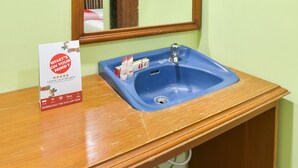 A bathroom with a wooden vanity, a blue sink, and a mirror. - Hotel Sekar Ayu (Yogyakarta)