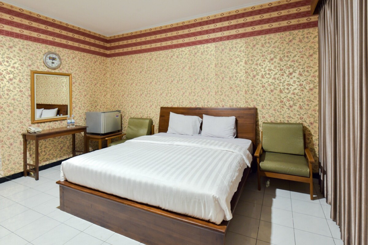 Una habitación de hotel con una cama grande, televisión, escritorio y una silla.