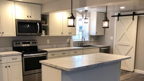 Een moderne keuken met witte kasten, roestvrijstalen apparatuur en een groot eiland.