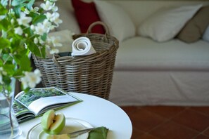 A wicker basket with a rolled-up towel and a book on a table, a green apple, and a glass of water. - Cascina San Giorgio (Valenza)
