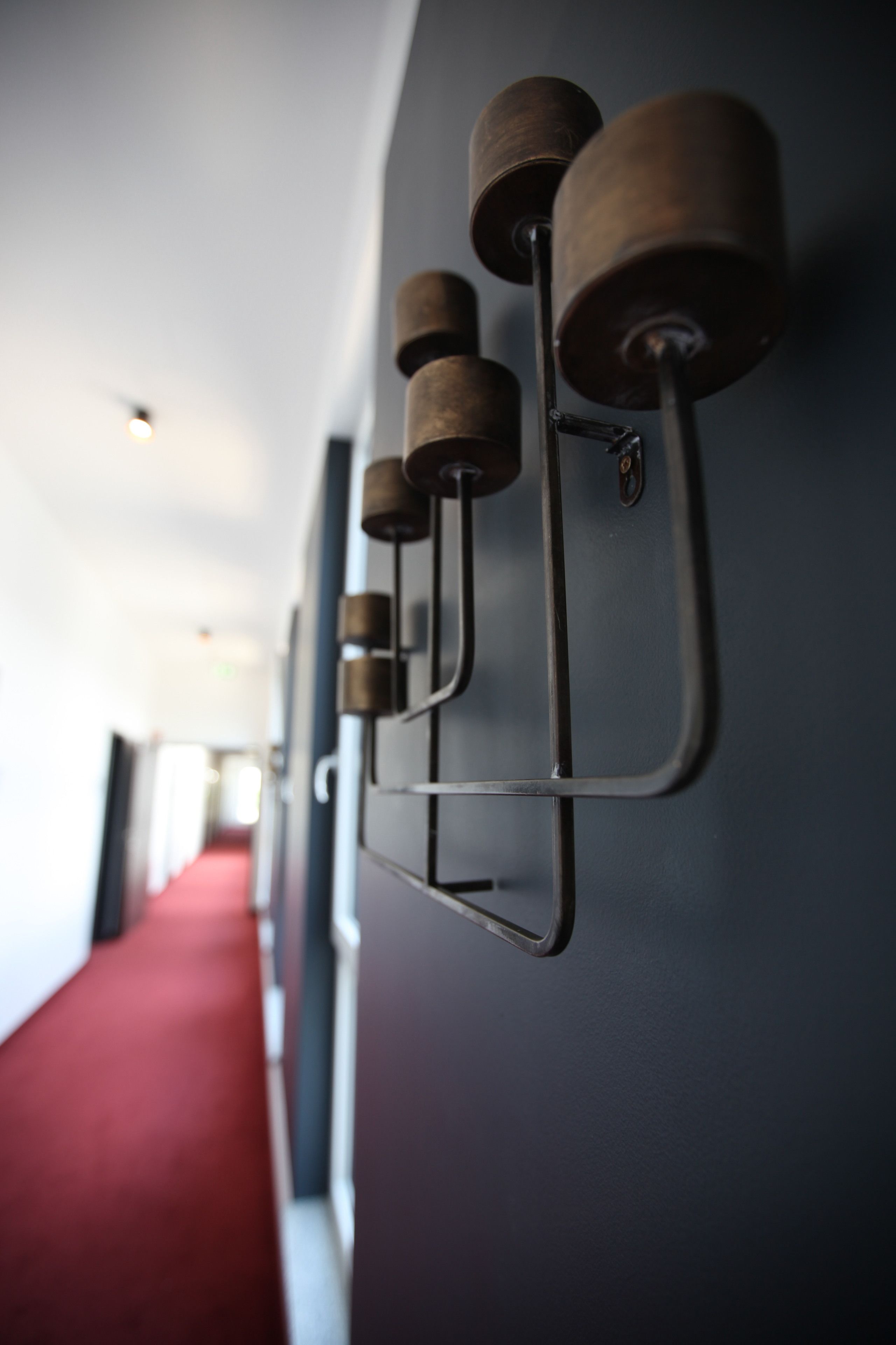 A corridor with a red carpet and wall-mounted cylindrical objects.