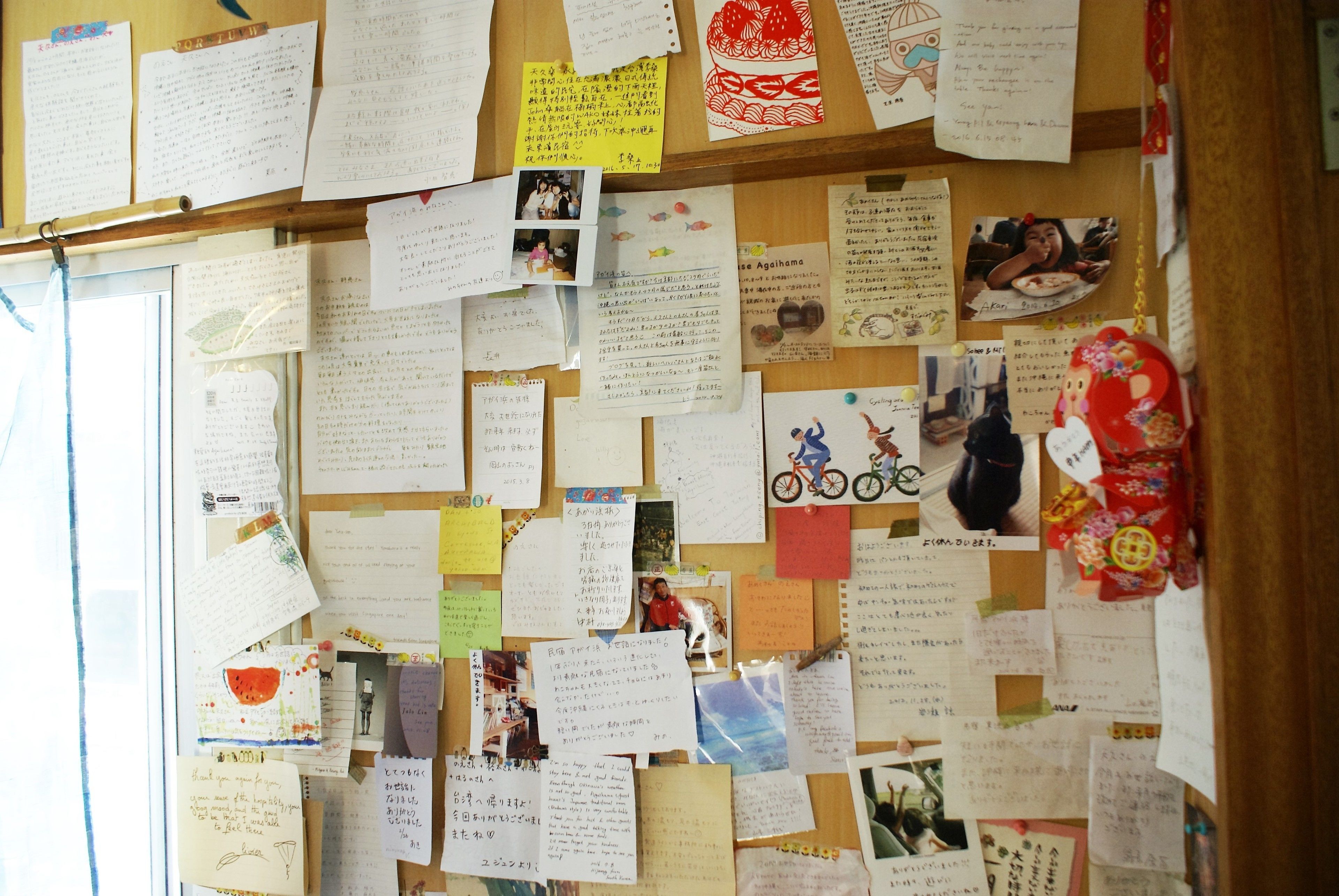 A bulletin board with various notes, photos, and drawings pinned to it.