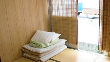 A room with tatami flooring, a bed with pillows, a sliding door, and an air conditioning unit.