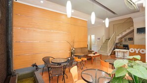 A modern hotel lobby with wooden panel walls, multiple seating areas, a staircase, and a reception desk. - OYO 450 Semampir Residence (Surabaya)