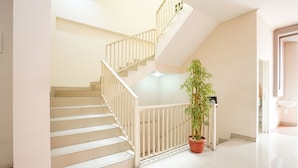 A staircase with white railings and a potted plant at the bottom. - OYO 450 Semampir Residence (Surabaya)