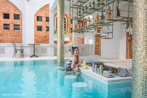 A pool area with a tiled wall, a shelf with bottles and glasses, and a chair. - Lanna Oriental Hotel (Chiang Mai)