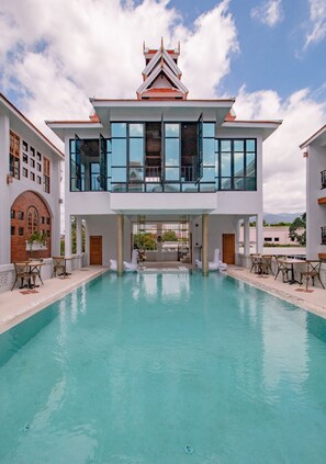 A modern building with a large pool in front. - Lanna Oriental Hotel (Chiang Mai)