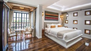 Un dormitorio espacioso con una cama grande, un balcón con asientos y vistas al verdor.