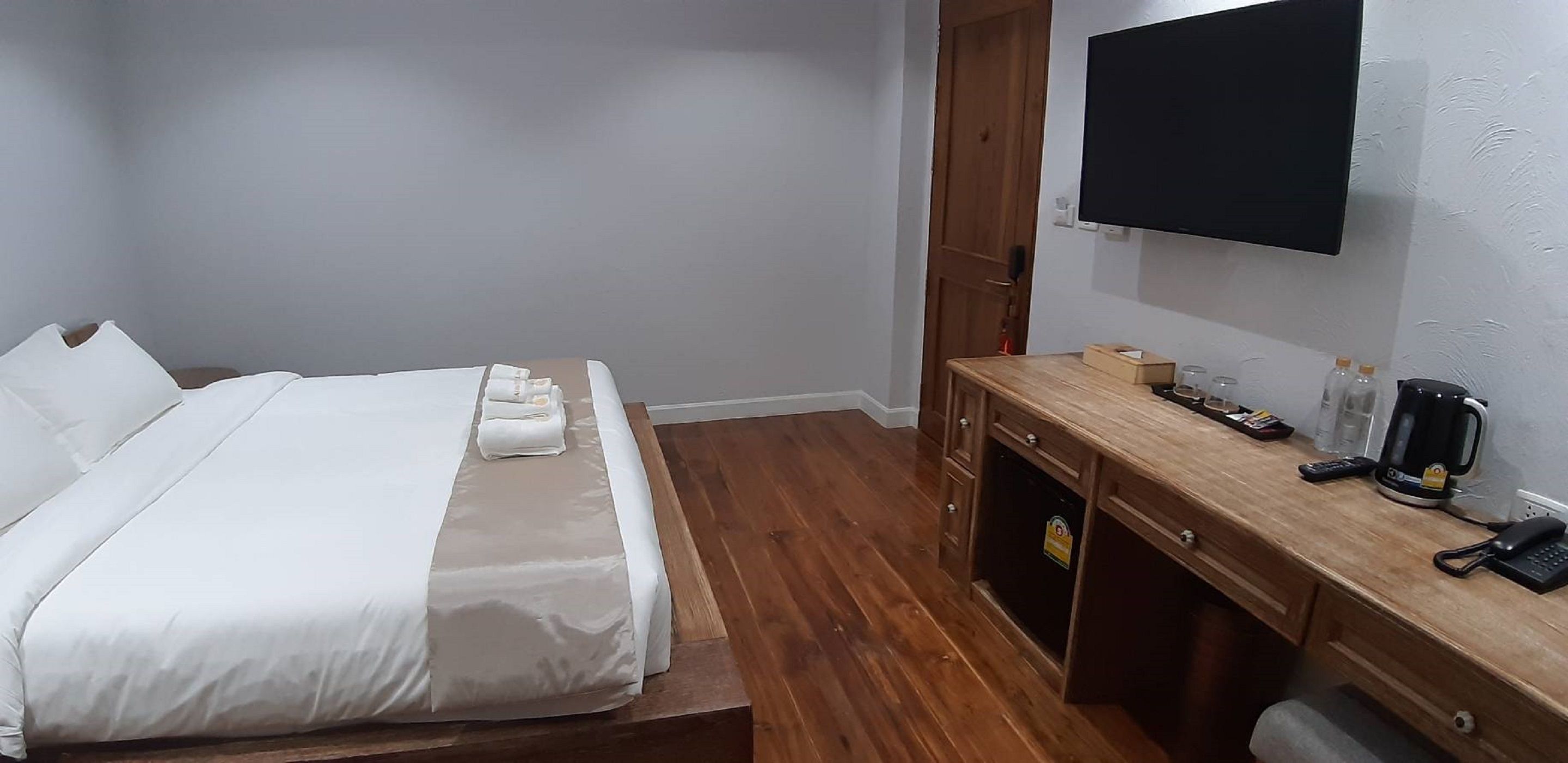 A hotel room with a bed, a desk with a coffee maker, a phone, and a TV mounted on the wall.