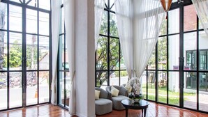 Una habitación amplia con ventanas grandes, un sofá y faroles colgantes.