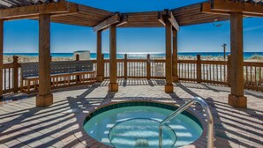 A wooden deck with a hot tub, wooden benches, and a view of the beach. - Pelican Beach Resort, Directly on the Beach w/breathtaking View (DESTIN)