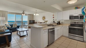 A modern kitchen with white cabinets, a central island, and stainless steel appliances. - Pelican Beach Resort, Directly on the Beach w/breathtaking View (DESTIN)