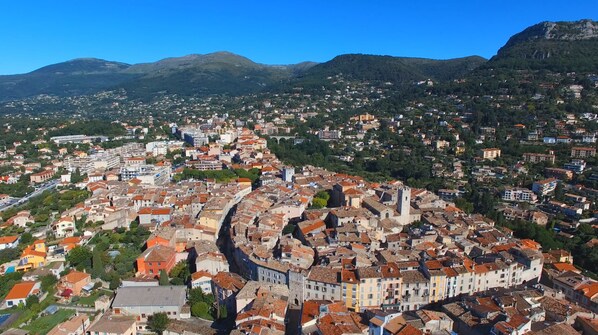 Vista panorâmica de uma cidade histórica, com uma praça central imponente, rodeada por edifícios residenciais e colinas ao fundo.