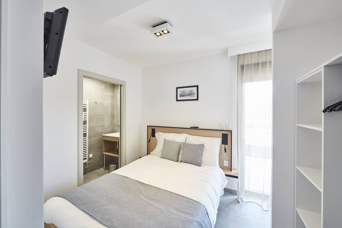 A modern bedroom with a bed, bedside tables, a wardrobe, and a window with curtains.