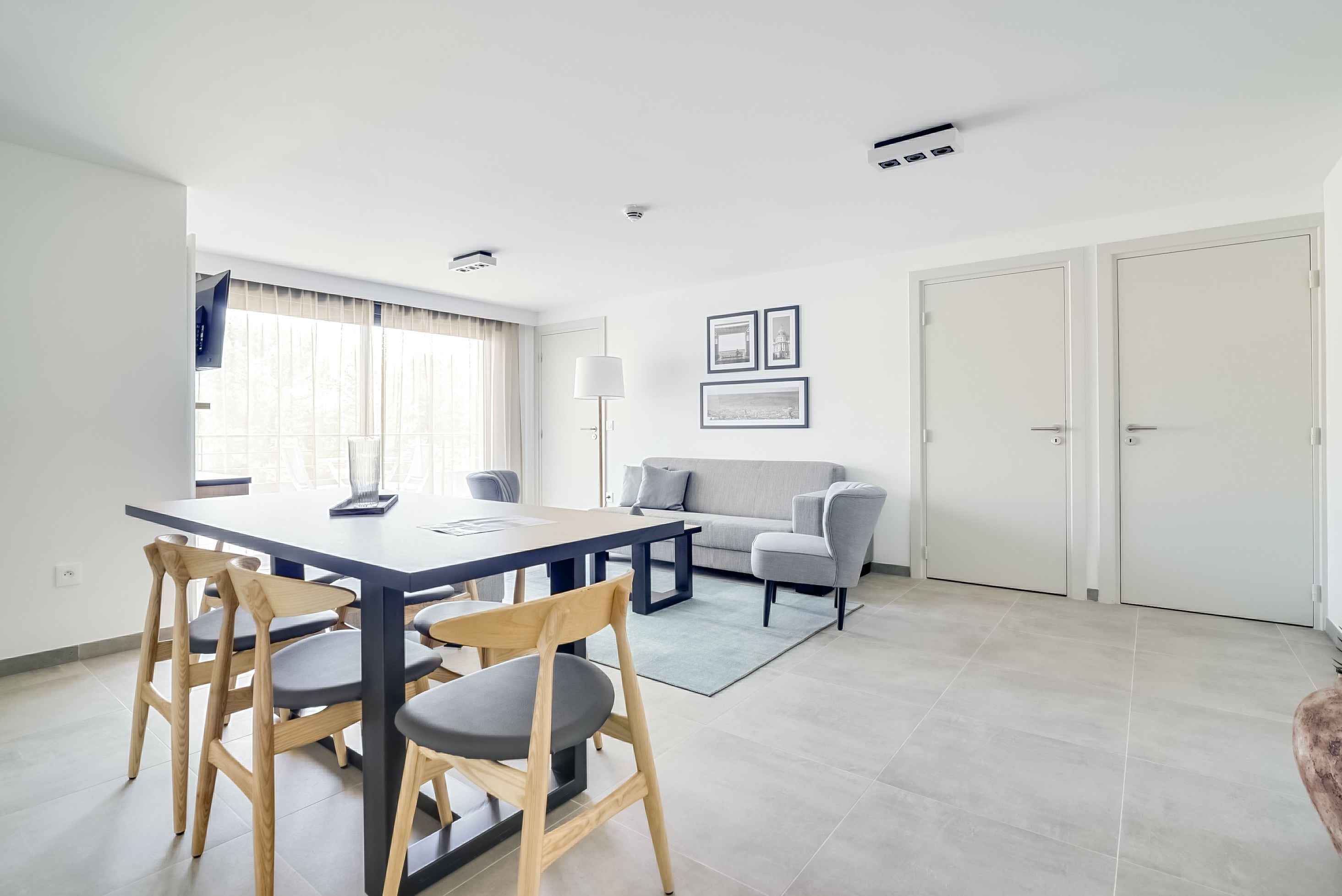 A modern living room with a dining area, featuring a sofa, a coffee table, and a dining table with chairs.