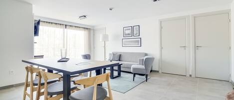 A modern living room with a dining area, featuring a sofa, a coffee table, and a dining table with chairs.