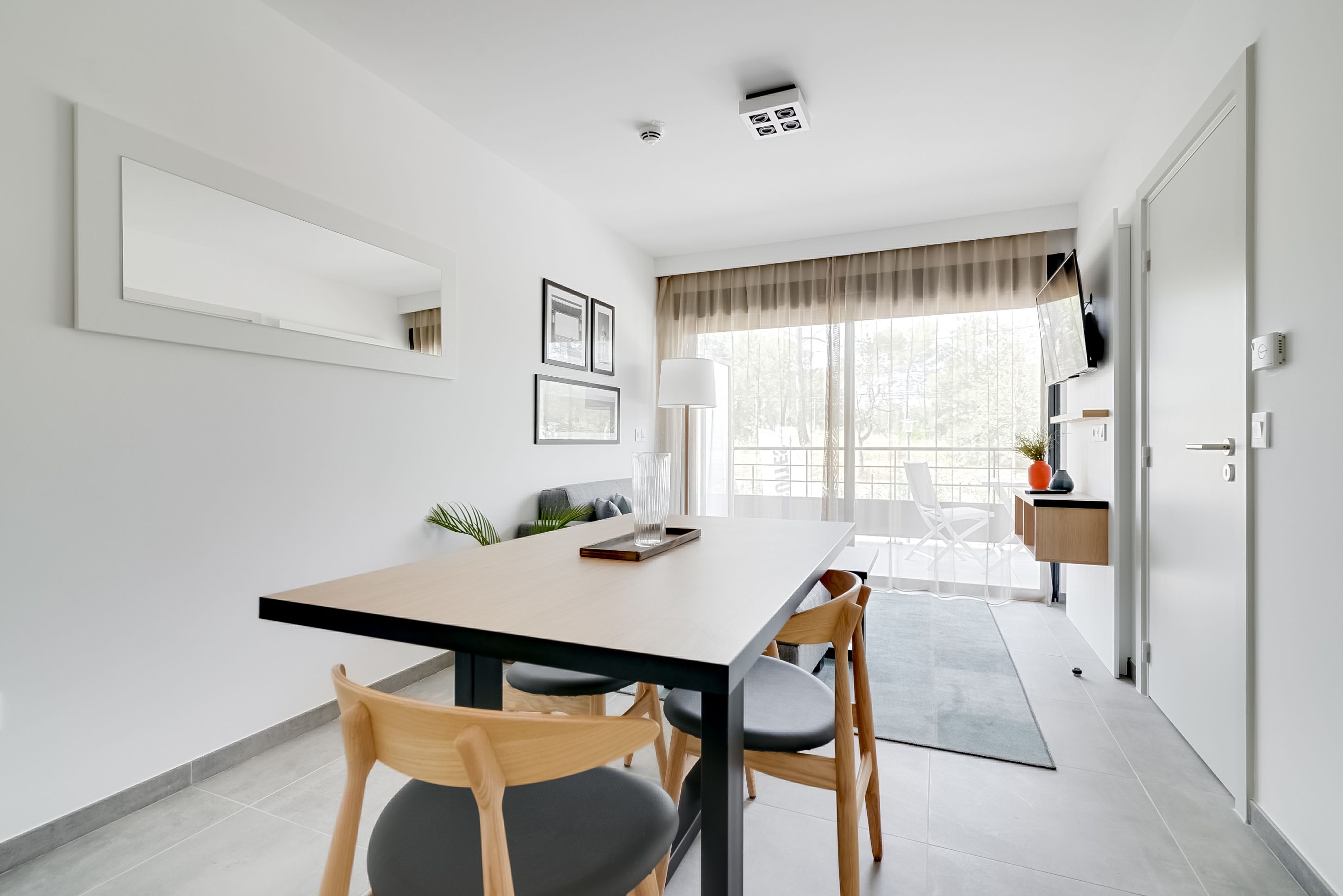 Un espace repas moderne avec une longue table, des chaises en bois et un design minimaliste.