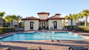 A pool area with a two-story building, palm trees, and a clear sky. - Villa Lago 1864 - 4BR 4BA - (Miramar Beach)