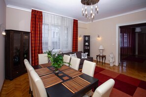 Un comedor con una mesa de madera, sillas blancas y un jarrón de flores.