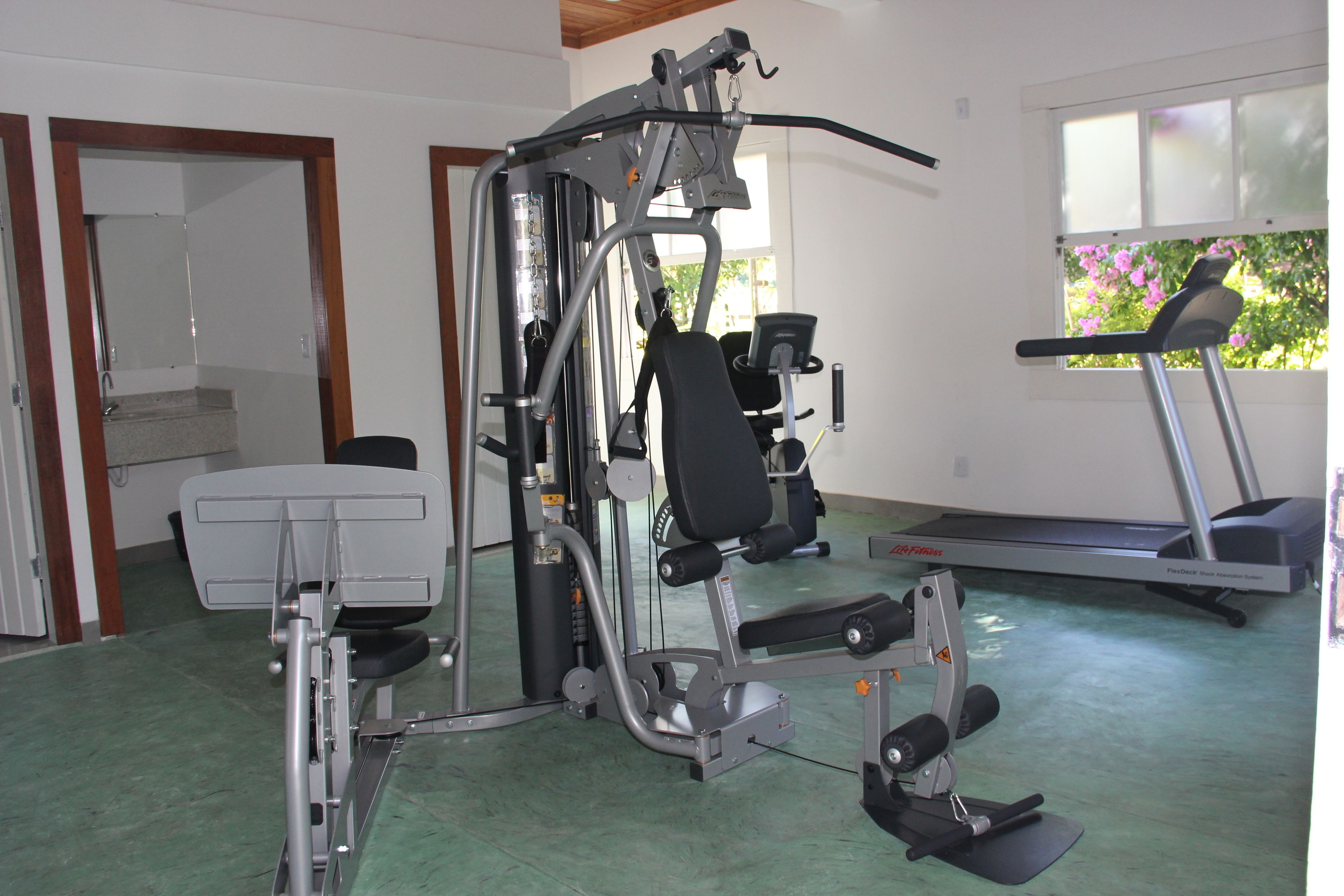 A gym with a treadmill, weight machines, and a bench.
