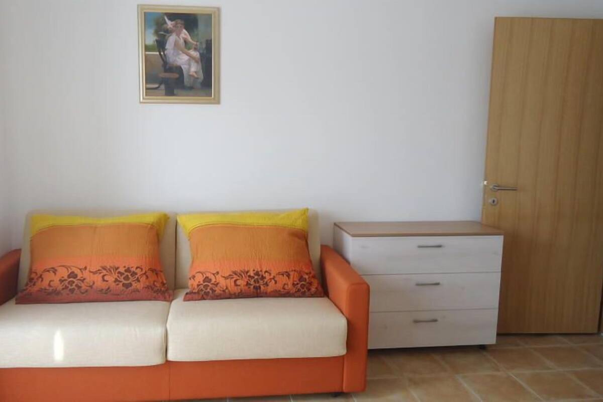 Een kamer met een bank, een klein nachtkastje en een houten garderobe.