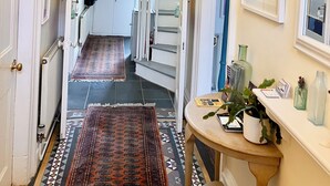 A hallway with a chandelier, a patterned rug, a staircase, and a table with a plant. - The Old Post House B&B (Penzance)
