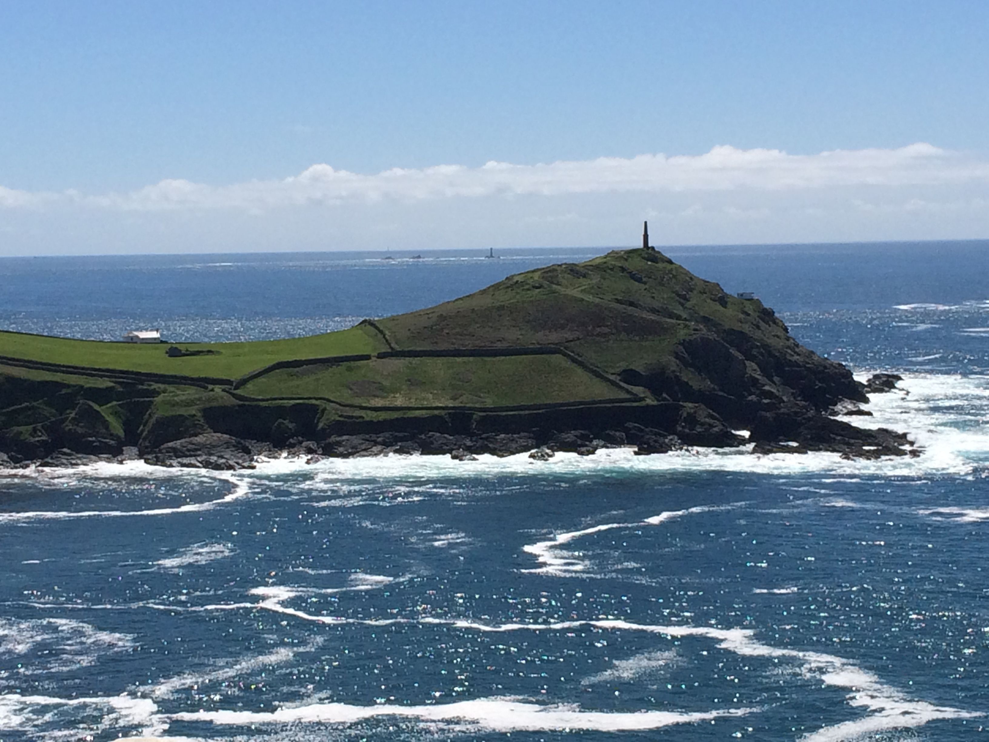 Un paysage côtier caractérisé par une colline imposante et un phare.