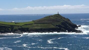 Un paysage côtier caractérisé par une colline imposante et un phare.