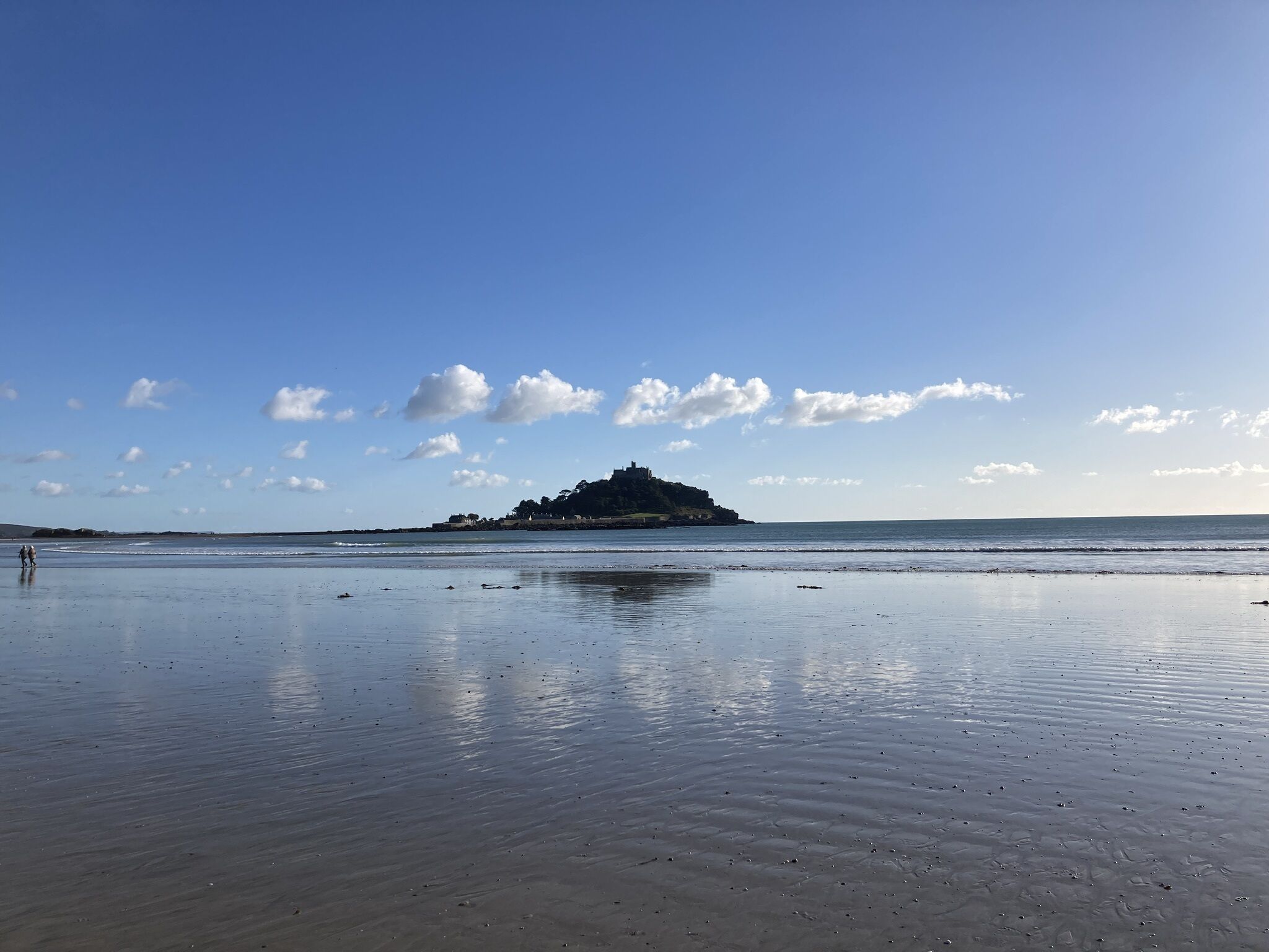 A beach with calm waters and a distant island.