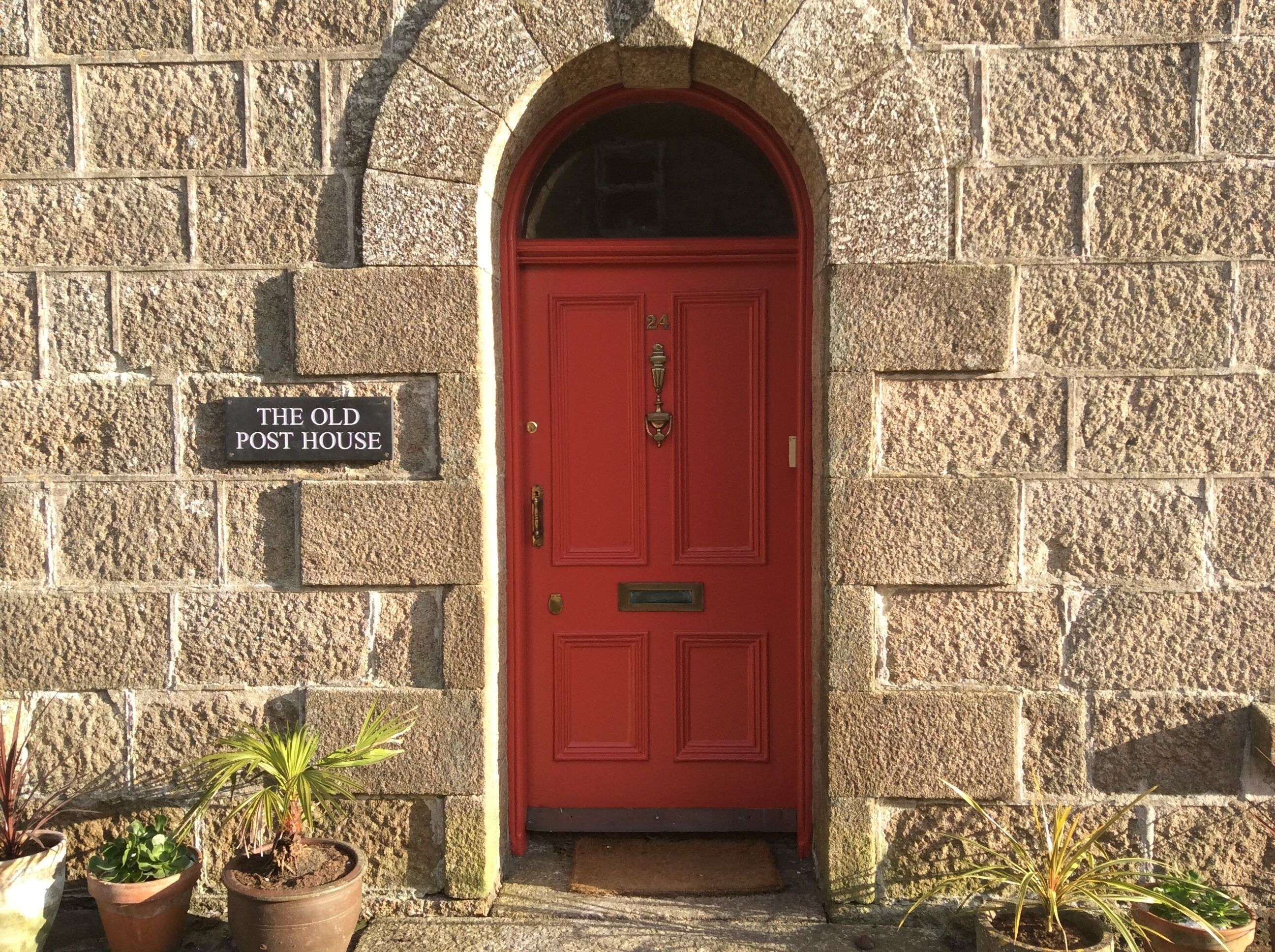 A stone building with a red door and a sign reading 'The Old Post House.'
