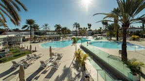 Poolbereich eines Resorts mit Liegestühlen und Palmen.