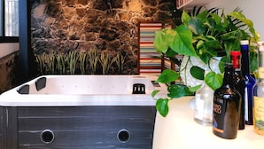 A modern bathroom with a stone wall, a bathtub, and various toiletries. - La Foresteria Garden Boutique B&B (Catania)