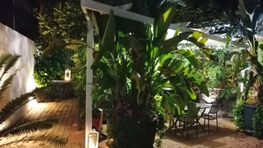 An outdoor patio area with a brick floor, potted plants, a table with chairs, and a white pergola structure. - La Foresteria Garden Boutique B&B (Catania)