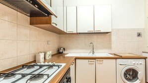 A kitchen with a gas stove, a sink, and a washing machine. - Indipendenza Retreats (Bologna)
