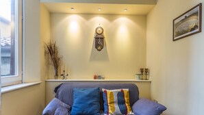 A cozy corner with a cushioned seating area, a wall-mounted clock, and a shelf with decorative items. - Indipendenza Retreats (Bologna)